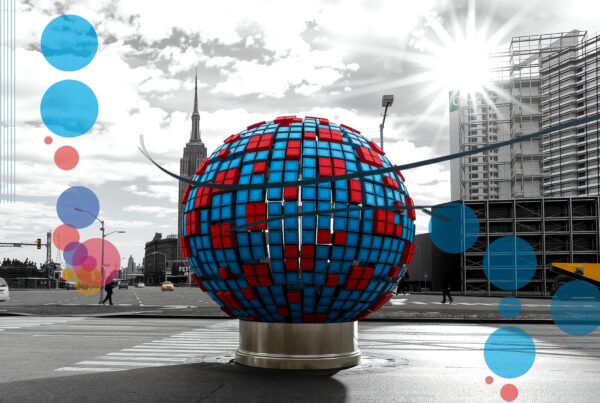 A vibrant geometric sphere in a bustling urban setting, highlighting modern art contrasts with monochromatic cityscape.